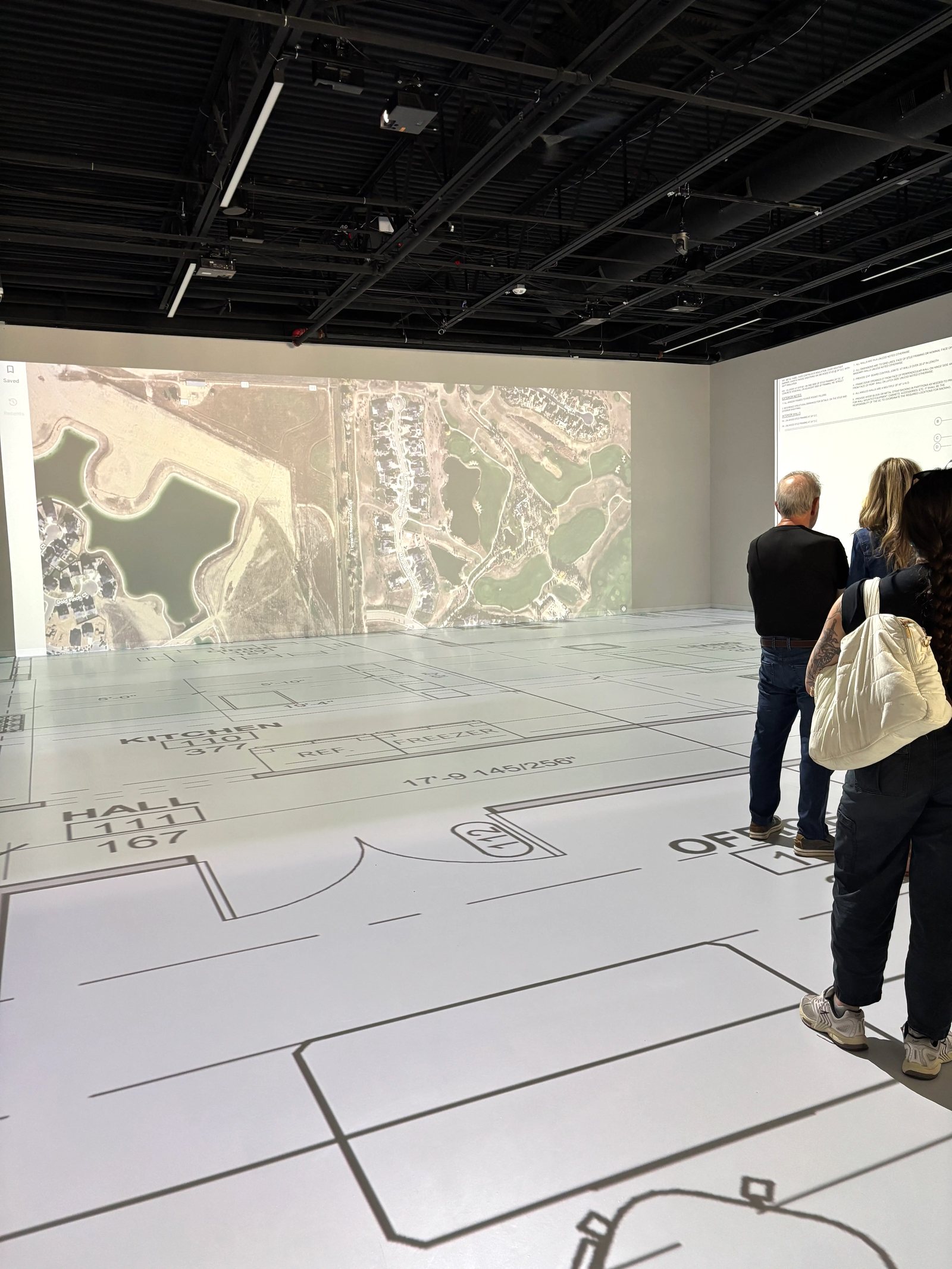 Aerial map projected on the studio wall with floor plans underfoot
